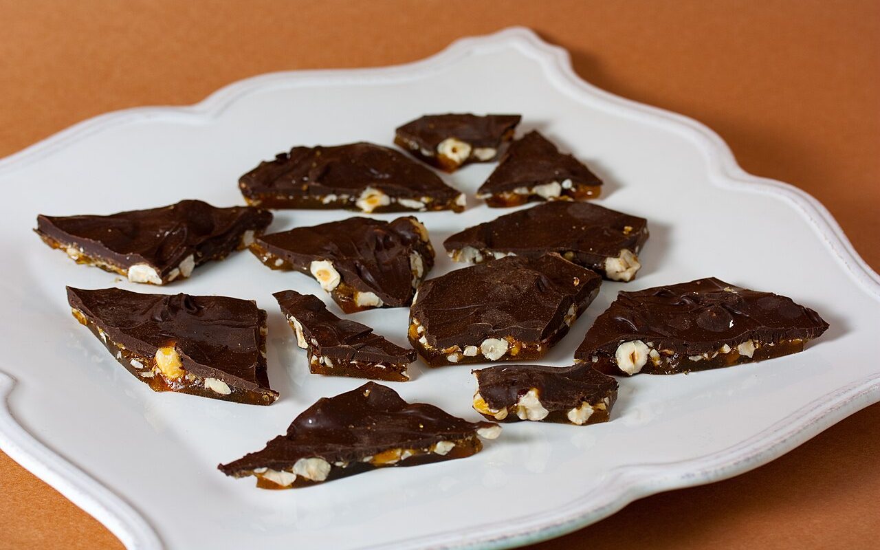 Shards of chocolate bark with hazelnuts on a white plate