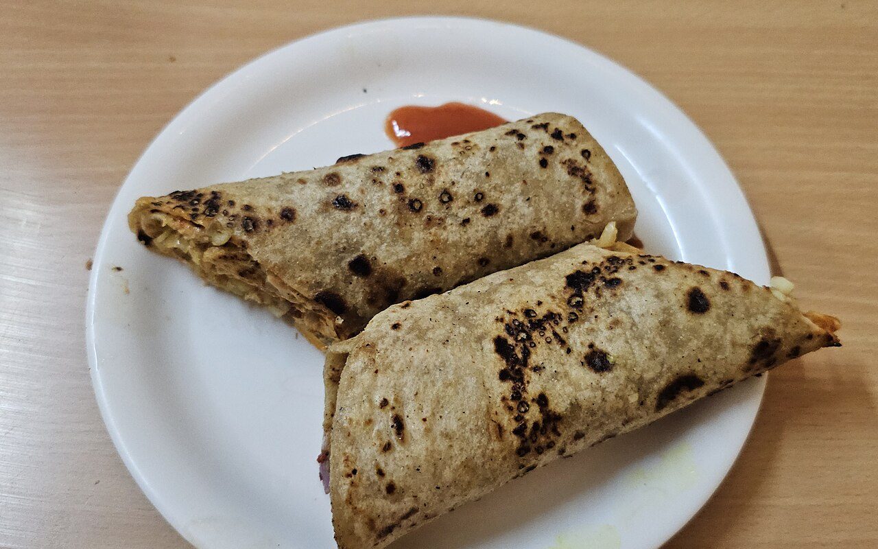 Two paratha rolls on a plate with a little ketchup