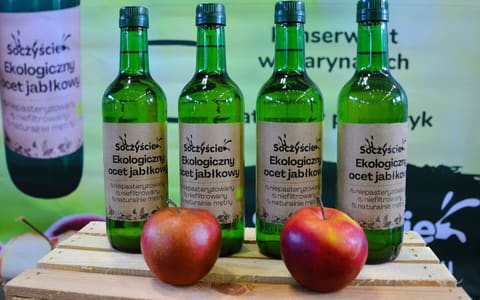Bottles of organic apple cider vinegar beside two red apples