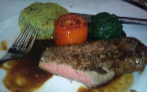 A kangaroo steak served with a stuffed tomato, spinach and potato