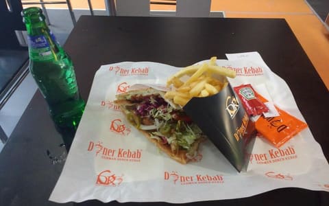 A doner kebab with jalapeños and fries on German Doner Kebab branded paper
