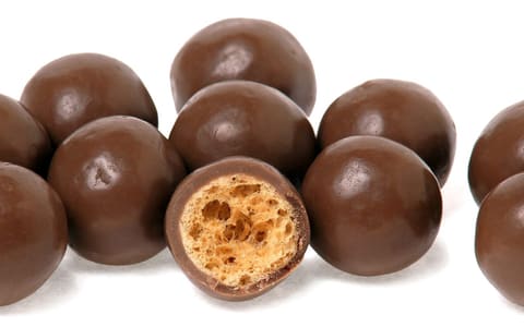 Maltesers chocolate balls, one split to show the honeycombed malt centre