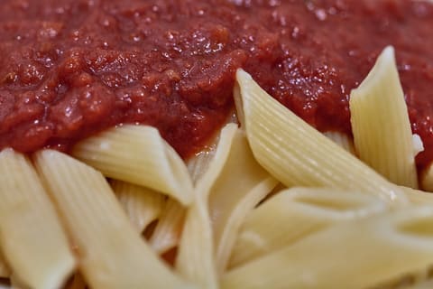 Close-up of ridged penne pasta with a chunky red tomato sauce