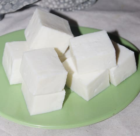 White homemade paneer cubes piled on a light green plate