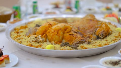 Qatari machbous: roasted chicken on a silver platter of golden spiced rice with lemon slices