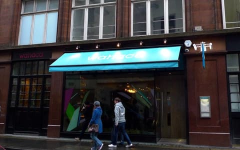 A Wahaca restaurant front with a turquoise awning in Soho, London