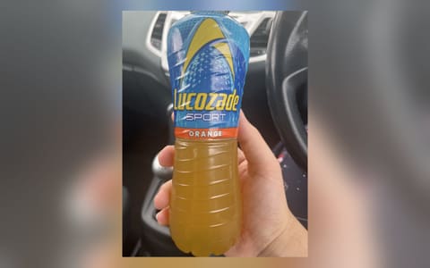 A bottle of Lucozade Sport Orange held in a hand