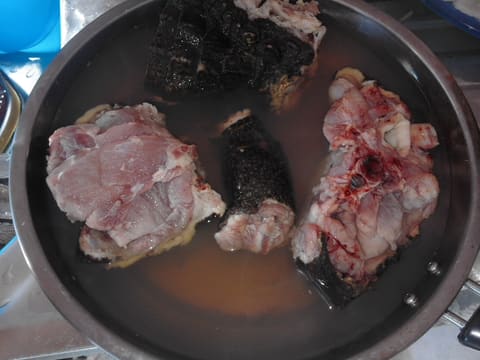 Raw crocodile meat pieces with scaly skin in a cooking pan