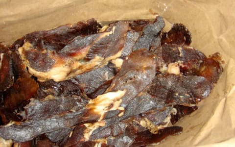 Strips of homemade beef jerky in a brown paper bag