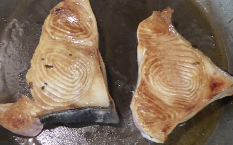 Two shark steaks pan-frying in oil
