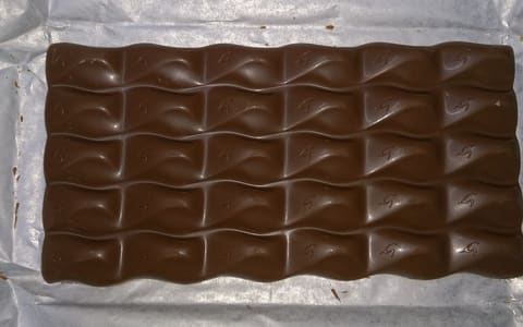 An unwrapped Galaxy bar on its foil, with the G logo on every square