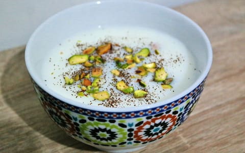 A bowl of sahlab topped with crushed pistachio and cinnamon