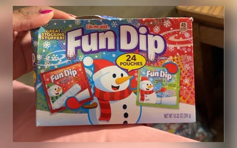 A 24-pouch holiday box of Lik-m-aid Fun Dip candy held in one hand