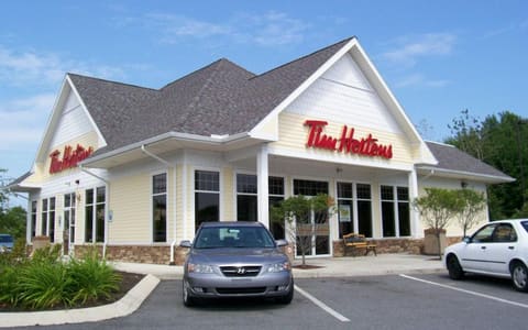 A Tim Hortons restaurant with its red sign, seen from the car park