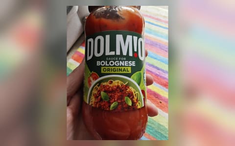 A jar of Dolmio Sauce for Bolognese Original held in a hand