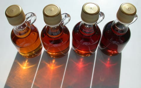 Four bottles of maple syrup, from golden to dark amber
