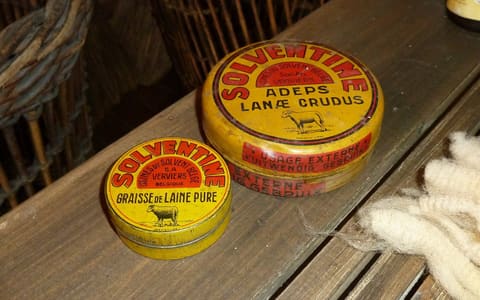 Vintage tins of crude lanolin (wool grease) beside a tuft of raw sheep's wool