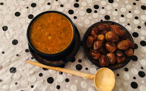 A bowl of Moroccan harira soup beside a bowl of dates