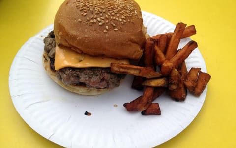 A Bleecker cheeseburger with fries on a paper plate