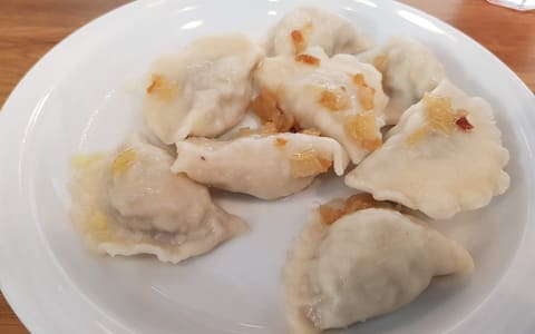 A plate of Polish pierogi ruskie topped with fried onion