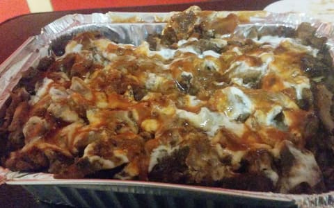 A Halal snack pack in a foil tray: doner meat over chips with garlic, barbecue and chilli sauces, from a kebab shop in St Kilda, Melbourne